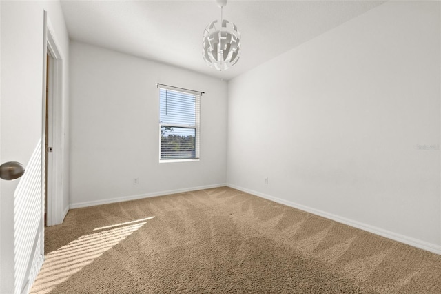 carpeted spare room with a chandelier