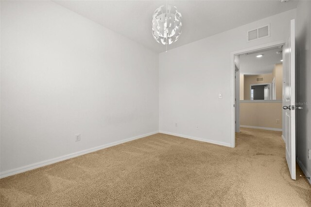 carpeted spare room with a chandelier