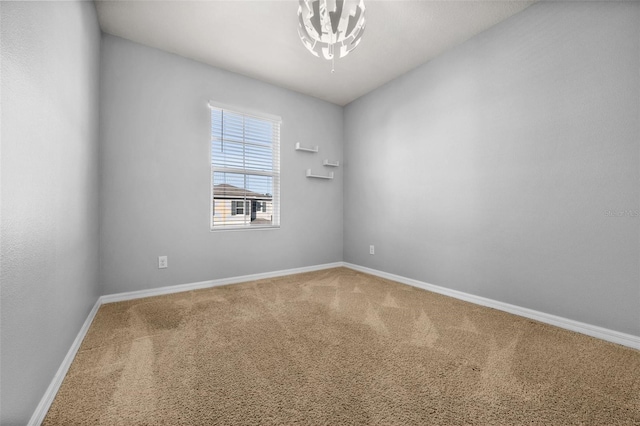 empty room with carpet floors and a notable chandelier