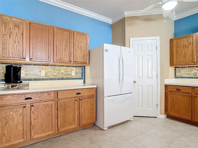 kitchen featuring backsplash, light countertops, crown molding, and freestanding refrigerator