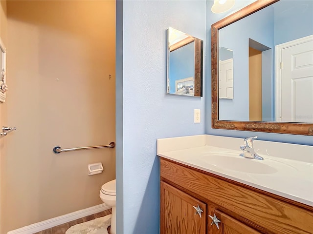 bathroom featuring vanity, toilet, and baseboards