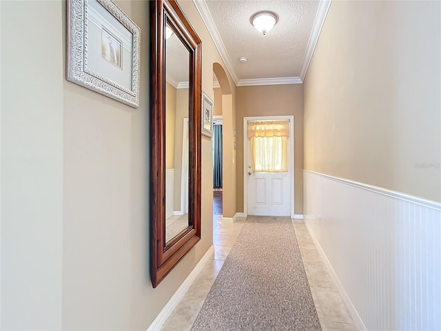 5255 Athens Way, Venice, FL 34293 - corridor featuring arched walkways, a textured ceiling, crown molding, light tile patterned floors, and wainscoting