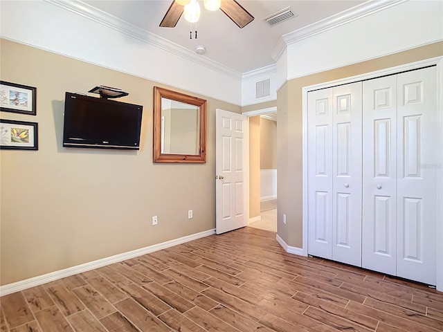 unfurnished bedroom with a closet, ceiling fan, crown molding, and wood-type flooring