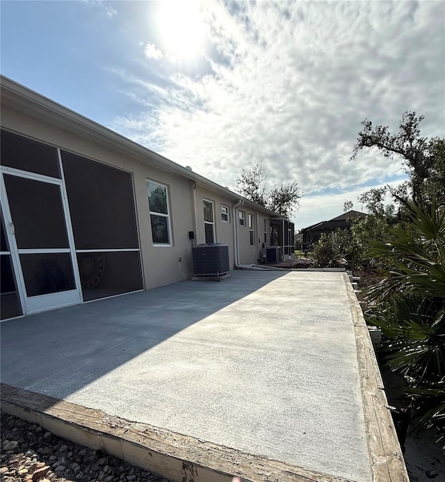 exterior space featuring a patio, cooling unit, and stucco siding