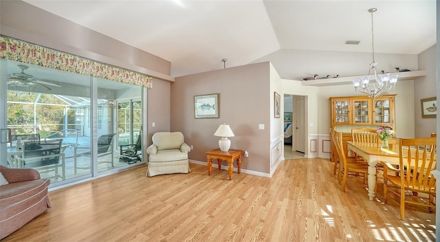 living area featuring a notable chandelier, vaulted ceiling, and light wood-type flooring