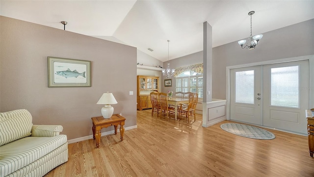 entryway with french doors, light hardwood / wood-style floors, an inviting chandelier, and lofted ceiling