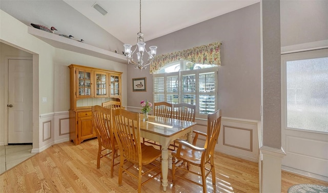 dining area with a chandelier, light wood-type flooring, and lofted ceiling