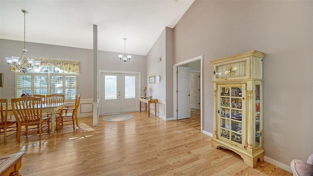 entrance foyer with french doors, high vaulted ceiling, light hardwood / wood-style floors, and a notable chandelier