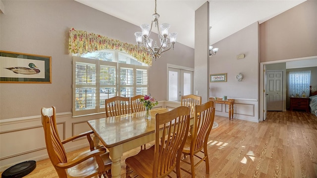 dining space with light hardwood / wood-style floors, french doors, and an inviting chandelier