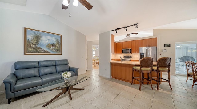 kitchen featuring stainless steel appliances, a kitchen breakfast bar, kitchen peninsula, lofted ceiling, and light tile patterned floors