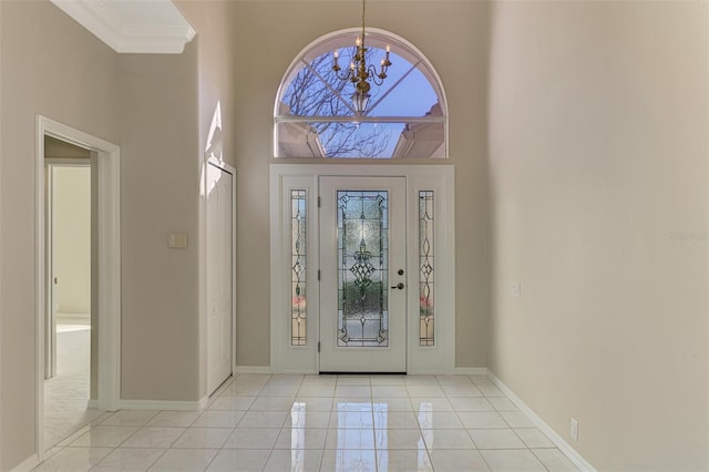 tiled foyer featuring a notable chandelier, a towering ceiling, and ornamental molding