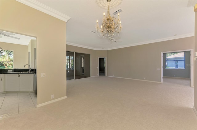 unfurnished living room featuring light carpet, ornamental molding, ceiling fan with notable chandelier, and a healthy amount of sunlight