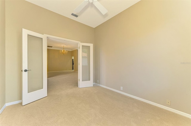 empty room with light carpet, french doors, ceiling fan with notable chandelier, and crown molding