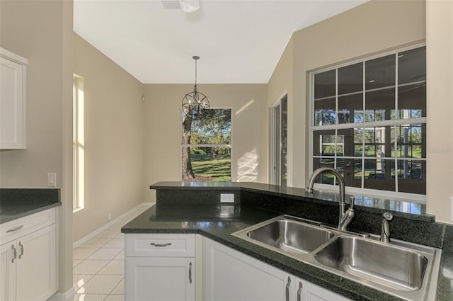 kitchen featuring decorative light fixtures, white cabinetry, sink, and light tile patterned floors