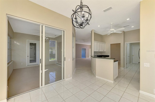 kitchen featuring white cabinetry, light tile patterned flooring, pendant lighting, and ceiling fan with notable chandelier