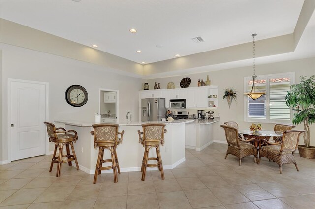 kitchen with a breakfast bar, appliances with stainless steel finishes, white cabinetry, and pendant lighting