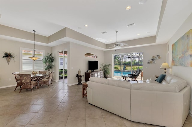 tiled living room featuring a tray ceiling and ceiling fan