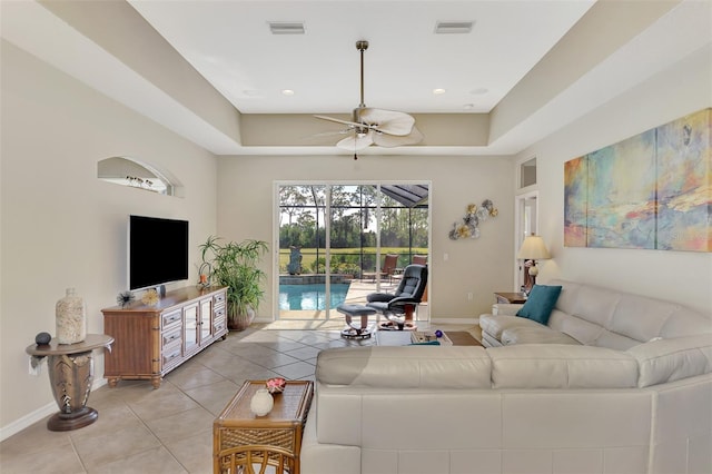 tiled living room featuring ceiling fan and a tray ceiling