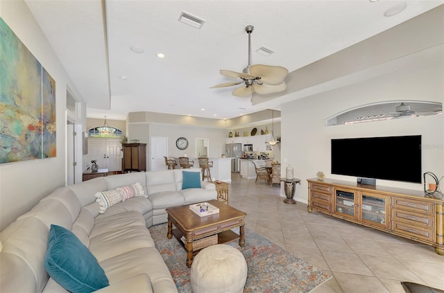 tiled living room with a raised ceiling and ceiling fan