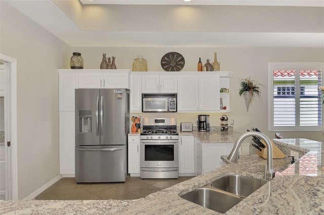 kitchen featuring appliances with stainless steel finishes, light tile patterned floors, white cabinetry, and sink