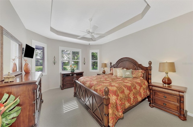 bedroom with a tray ceiling, ceiling fan, and light colored carpet