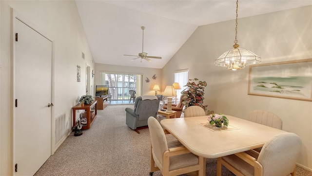 carpeted dining area featuring ceiling fan with notable chandelier and high vaulted ceiling