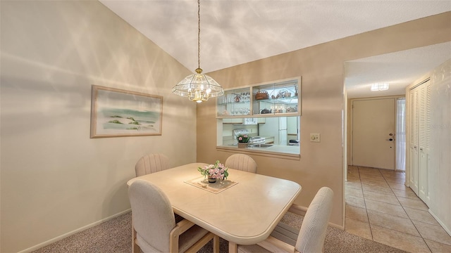 tiled dining space with lofted ceiling and a notable chandelier