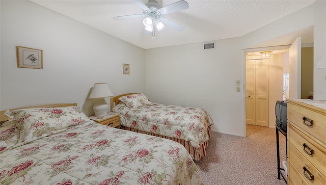 carpeted bedroom with ceiling fan, a closet, and a textured ceiling