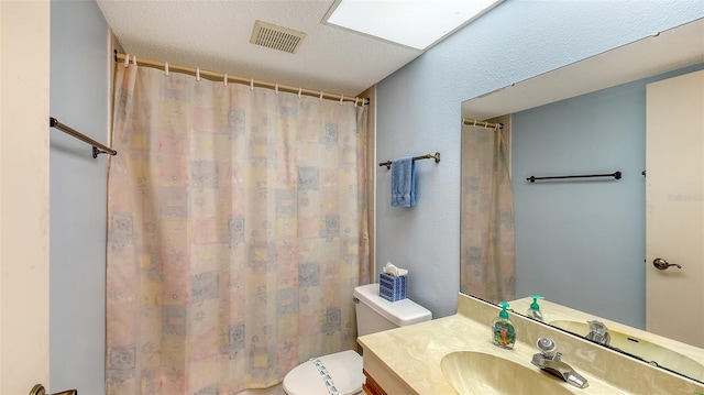 bathroom featuring a textured ceiling, vanity, and toilet