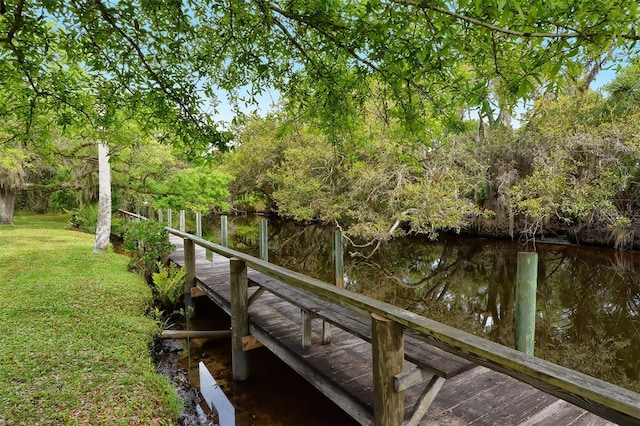 view of dock featuring a water view and a lawn