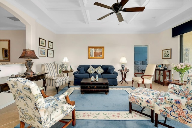 living room featuring ceiling fan, coffered ceiling, beamed ceiling, light tile patterned flooring, and ornamental molding