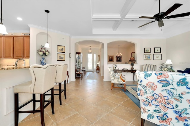 tiled living room featuring beamed ceiling, ceiling fan with notable chandelier, ornamental molding, and coffered ceiling