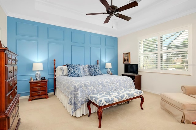 carpeted bedroom with a tray ceiling, ceiling fan, and ornamental molding