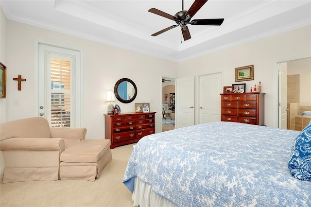 carpeted bedroom with ceiling fan, a raised ceiling, crown molding, and ensuite bath