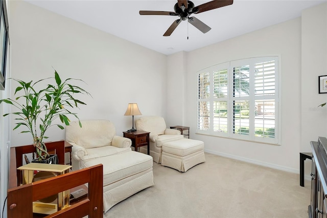 living area featuring light colored carpet and ceiling fan