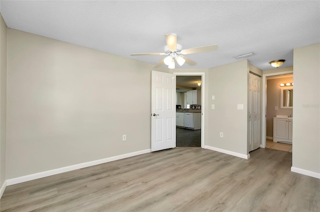 unfurnished room with ceiling fan, a textured ceiling, and light wood-type flooring