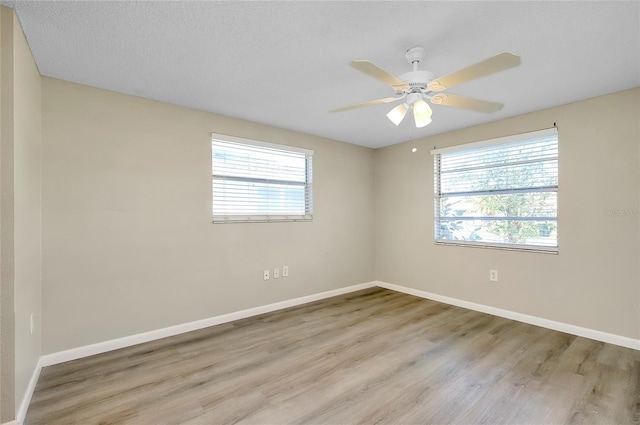 unfurnished room featuring ceiling fan, plenty of natural light, light hardwood / wood-style flooring, and a textured ceiling