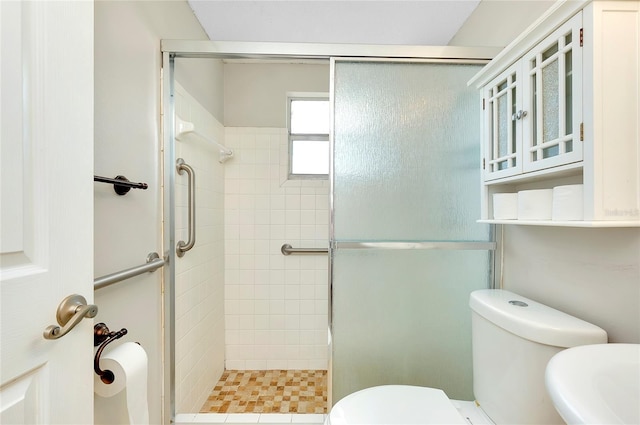 bathroom featuring toilet and a shower with door