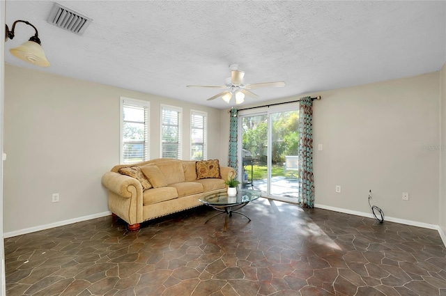 living room featuring ceiling fan and a textured ceiling