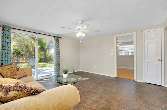 living room with ceiling fan and a textured ceiling