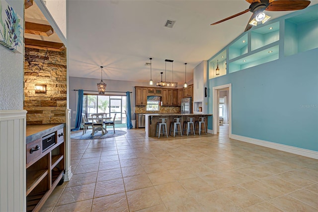 interior space with decorative backsplash, a kitchen breakfast bar, kitchen peninsula, ceiling fan, and stainless steel refrigerator