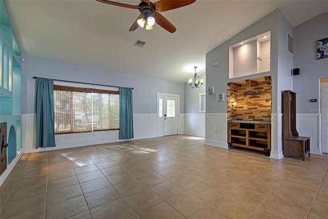 unfurnished living room featuring light tile patterned floors, ceiling fan with notable chandelier, vaulted ceiling, and french doors