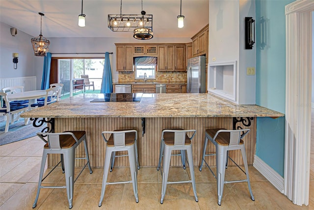 kitchen featuring a breakfast bar area, sink, hanging light fixtures, and appliances with stainless steel finishes