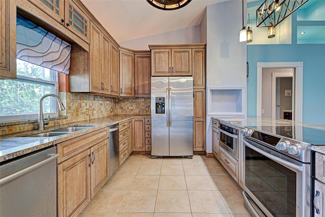 kitchen with light stone countertops, appliances with stainless steel finishes, vaulted ceiling, sink, and light tile patterned flooring