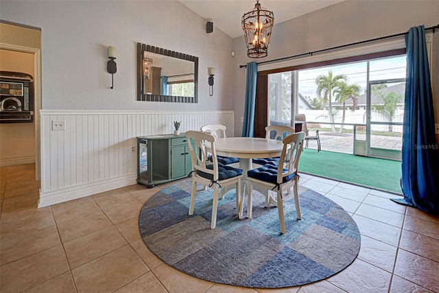 dining room with light tile patterned floors, a chandelier, and lofted ceiling