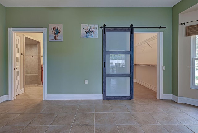 spare room with a barn door and light tile patterned flooring