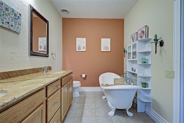 bathroom featuring tile patterned floors, a textured ceiling, vanity, toilet, and a tub