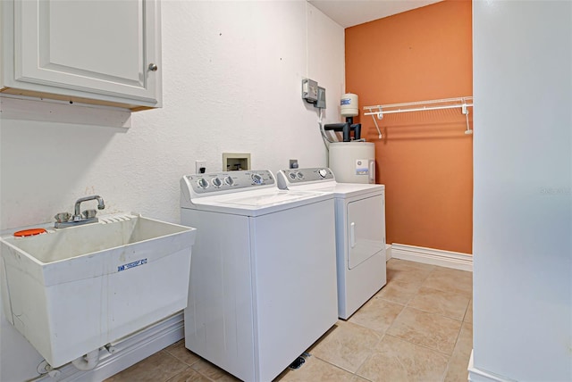 laundry area featuring cabinets, sink, washing machine and dryer, light tile patterned floors, and water heater