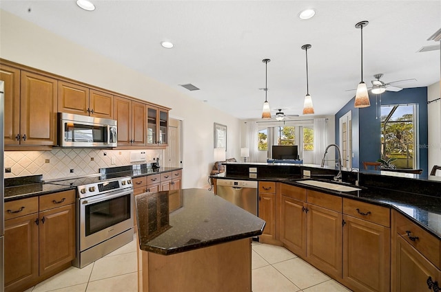 kitchen with pendant lighting, sink, ceiling fan, appliances with stainless steel finishes, and a kitchen island