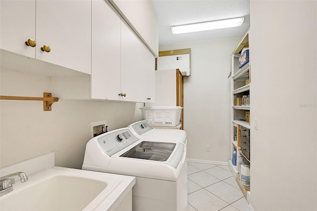 clothes washing area with washer and dryer, light tile patterned floors, cabinets, and sink